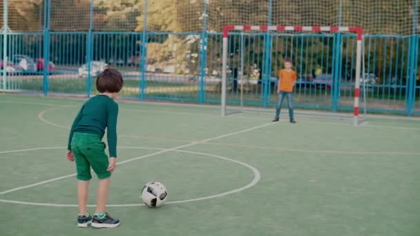 Um estudante chuta uma bola de futebol no gol, um segundo estudante pega a bola — Vídeo de Stock