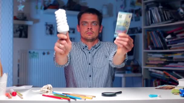 Man holds a light bulb and money in his hands — Stock Video