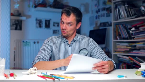 Guy looks at a paper document through a magnifying glass — Stock Video