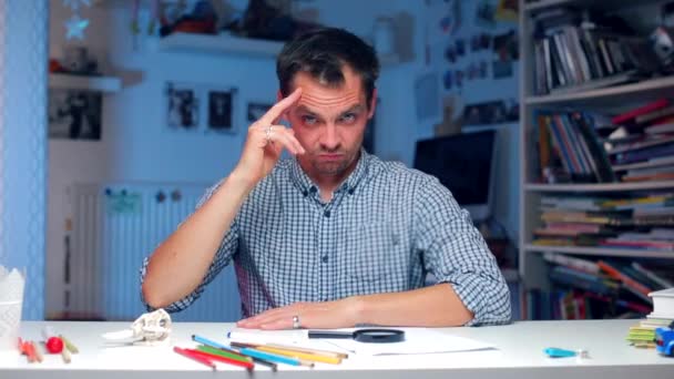 Um homem sentado à mesa mostra um gesto observando você — Vídeo de Stock