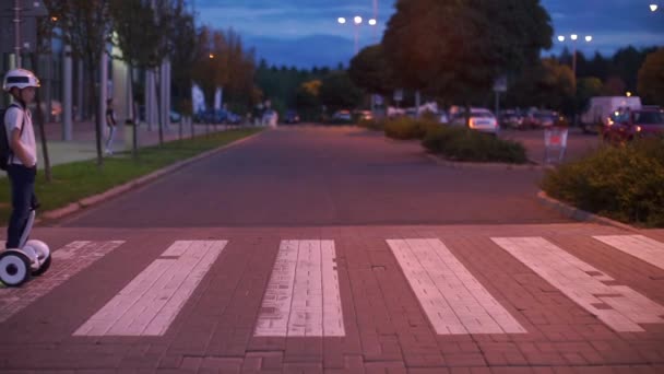 Zebrastreifen am Abend, auf dem ein Junge auf einem Kreisel fährt — Stockvideo