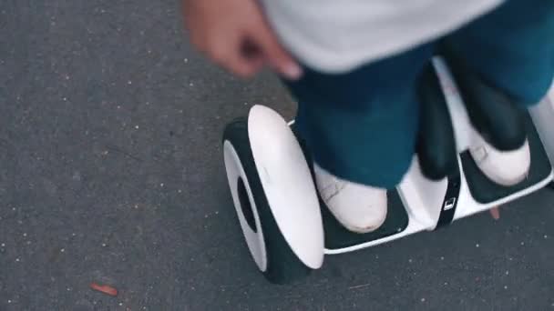 Um menino fica em um hoverboard, faz movimentos — Vídeo de Stock