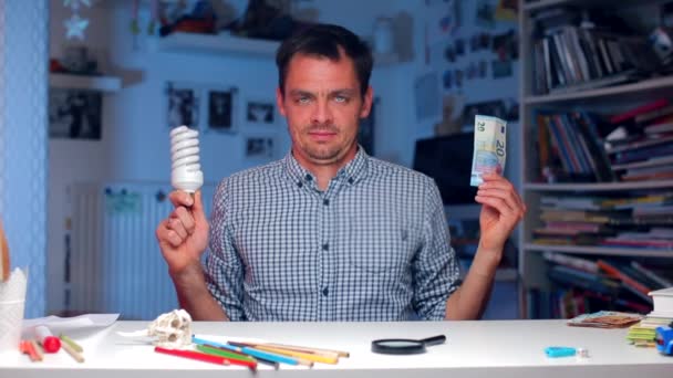 Una bombilla y un billete de 50 euros en manos de un hombre — Vídeo de stock
