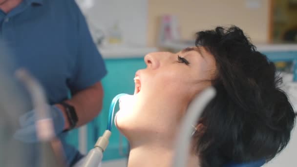 Il dentista inizia a trattare i denti di una ragazza in una clinica dentale — Video Stock