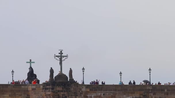Pont sur lequel les gens marchent près des croix et des statues — Video