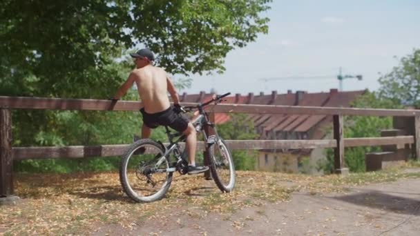 Хлопець без сорочки сидить на велосипеді, а потім починає рухатися — стокове відео