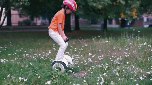 Adolescente si trova su un giroscooter sull'erba — Video Stock