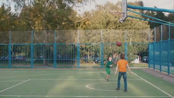 Twee tieners gooien een bal in een basketbalmand bij een les op school — Stockvideo