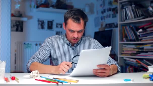 Un homme regarde les documents à travers une loupe, jette les documents — Video