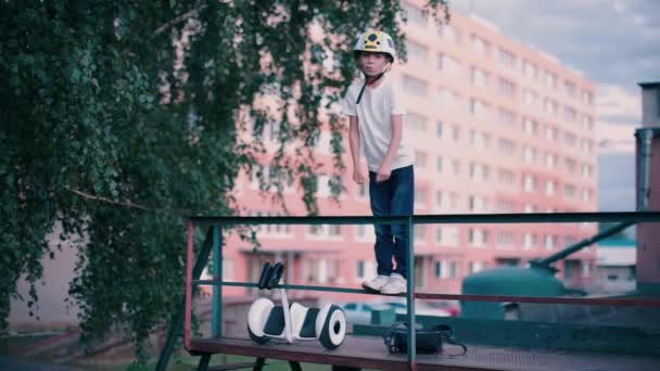 Junge tanzt auf Geländer neben Kreisel — Stockvideo