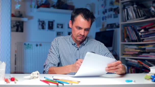 Vrolijke man aan tafel overweegt papieren documenten. — Stockvideo