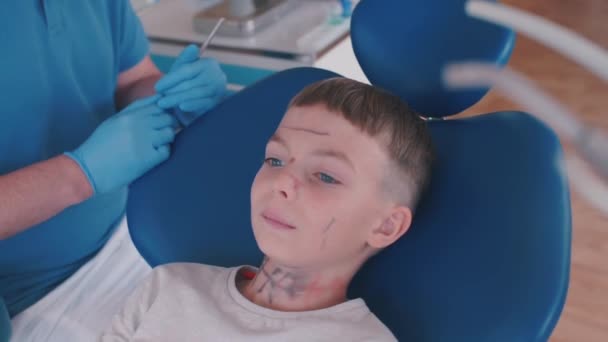 Teenager sedí v křesle u zubaře na recepci — Stock video