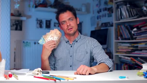 Le gars s'assoit à une table dans le bureau, agite un fan d'argent — Video