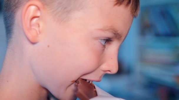 Chlapec kouše čokoládu svými zuby — Stock video