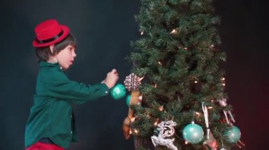Bir çocuk Noel ağacına oyuncak asar.