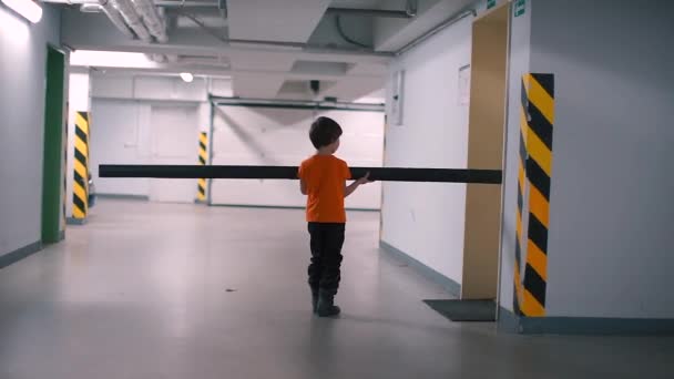 El niño pone una tubería larga en la puerta . — Vídeo de stock