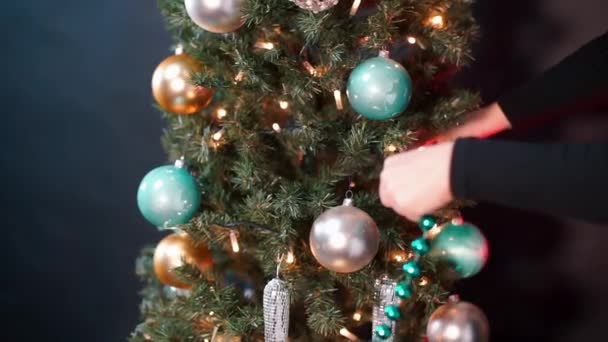 Nahaufnahme von Frauenhänden legen einen Kranz auf einen Weihnachtsbaum. — Stockvideo