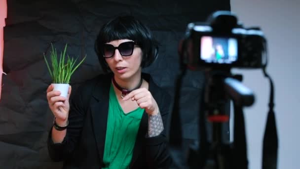 En sträng kvinna pratar med kameran om växter. Gör en video blogg. — Stockvideo