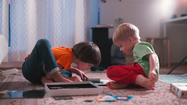 Τα παιδιά που κάθονται στο πάτωμα παίζουν επιτραπέζια παιχνίδια. — Αρχείο Βίντεο