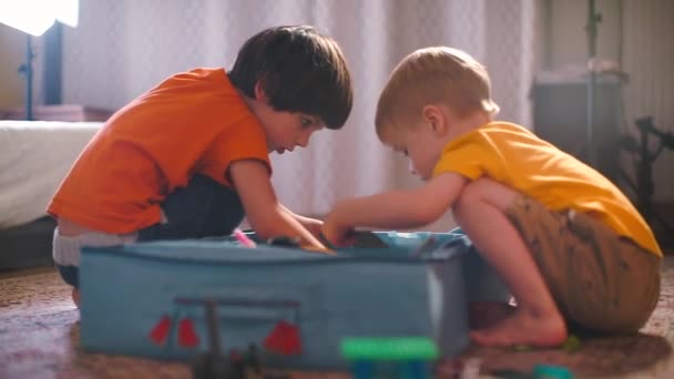 Kinderen zijn op zoek naar designerstukken in een doos. — Stockvideo