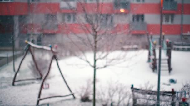 Schnee fällt vor dem Hintergrund eines Spielplatzes. — Stockvideo