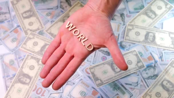 Het woord wereld in de palm van je hand tegen de achtergrond van ons dollars. — Stockvideo