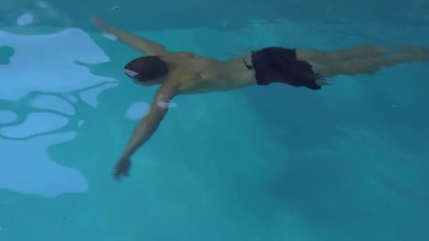 Человек ныряет в бассейн, плавает — стоковое видео