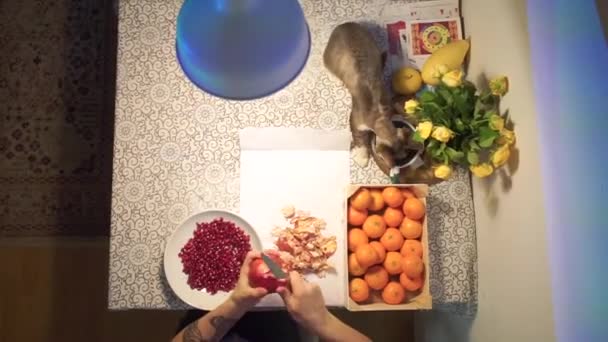 Handen zijn het reinigen van granaatappel in een plaat op tafel — Stockvideo