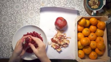 Kız elleri masadaki bir tabakta nar temizliyor.