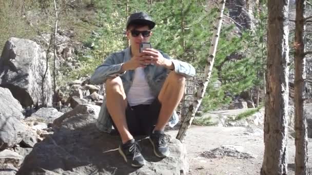 El tipo está sentado en una roca — Vídeo de stock