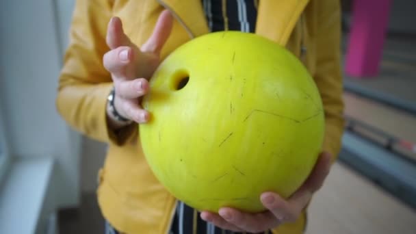 Chica sostiene una bola de boliche amarillo en sus manos — Vídeo de stock