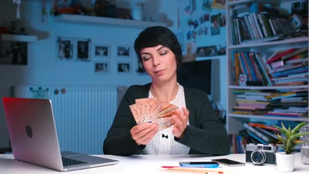 Flickan använder ett fan av pengar. Sitter vid ett bord i biblioteket. — Stockvideo