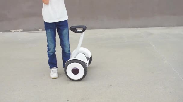 El niño se para cerca del giroscooter, se para en él y se da la vuelta — Vídeo de stock