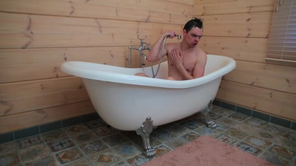 En glad kille tvättar sig på morgonen i badrummet under duschen. — Stockvideo