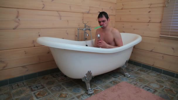 Un fou assis dans la salle de bain sonne sur la pomme de douche . — Video