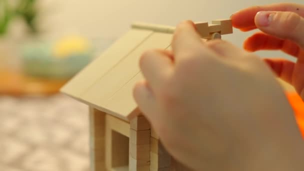 A boy is building a toy house. He puts the details the roof and seeks balance. — 비디오