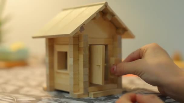 El niño pone un juguete en una casa pequeña . — Vídeo de stock