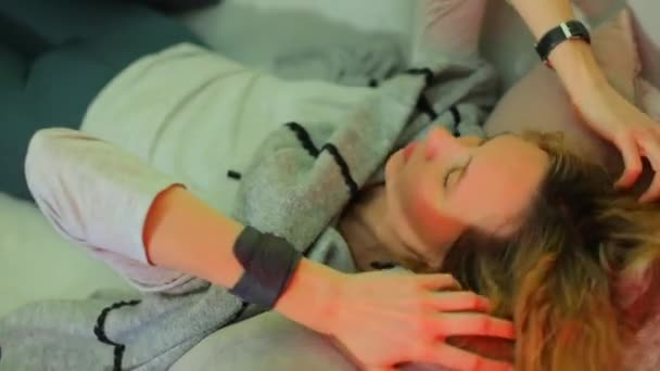 Uma menina relaxada está deitada em um sofá com as mãos no cabelo . — Vídeo de Stock