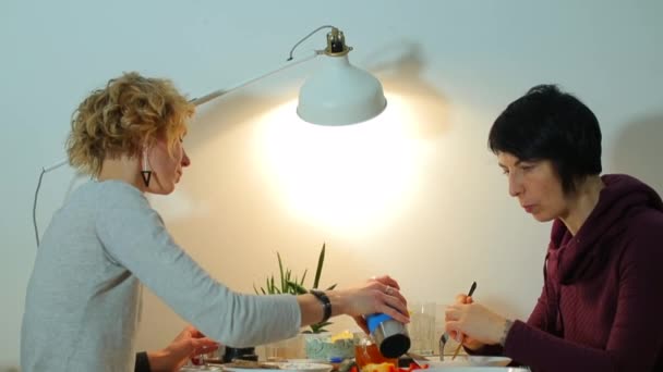 Två samkönade partner äter när de sitter vid bordet hemma. — Stockvideo