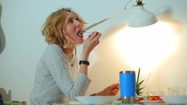 En kvinna äter när hon sitter vid ett bord. — Stockvideo