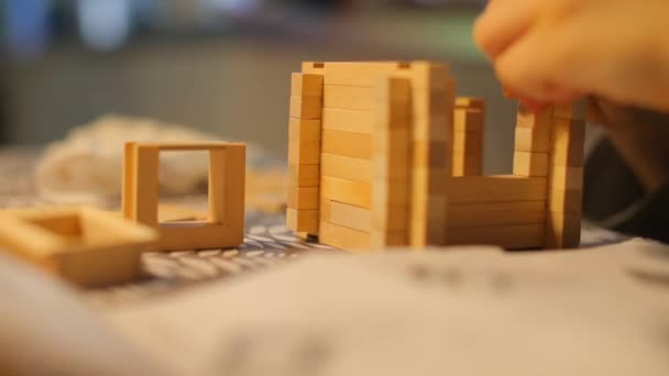 Κοντινό πλάνο παιδί χτίζει ένα μικρό σπίτι από έναν ξύλινο κατασκευαστή. — Αρχείο Βίντεο