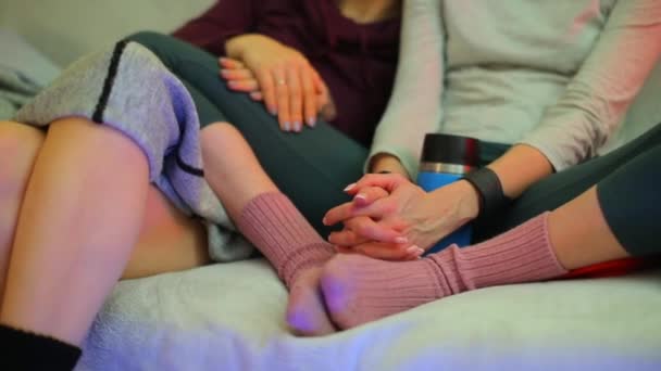 Крупним планом руки двох дівчат сидять і розмовляють на дивані . — стокове відео