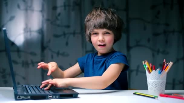 En pojke som sitter vid ett skrivbord i skolan trycker på en laptop knapp. — Stockvideo