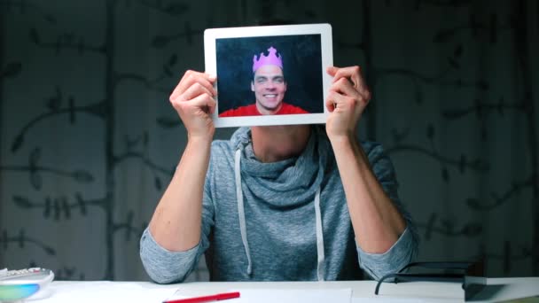 Een man zit aan een tafel met een tablet in zijn handen. — Stockvideo