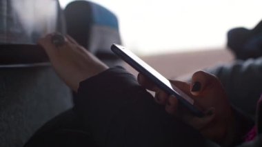 Toplu taşıma otobüsündeki bir kadının elindeki akıllı telefonun yakın çekimi..