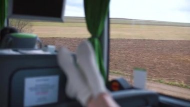Hareket halindeki otobüsteki bir gezginin bacakları..