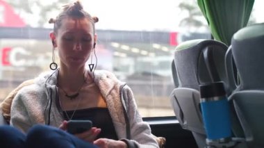 A woman sitting by the window rides on a public transport bus.