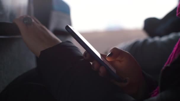 Een meisje met zwarte nagels gebruikt een smartphone in een trein. — Stockvideo