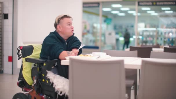 Disabled person sitting at a table in an office restaurant eating lunch. — Stock Video