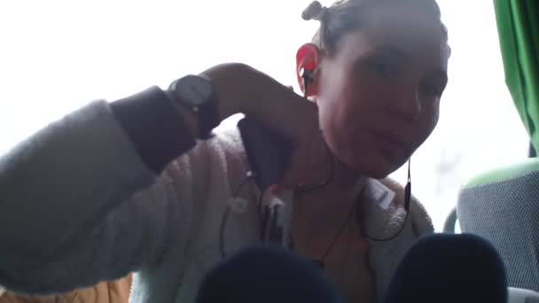 Женщина, сидящая в общественном транспорте слушает музыку — стоковое видео